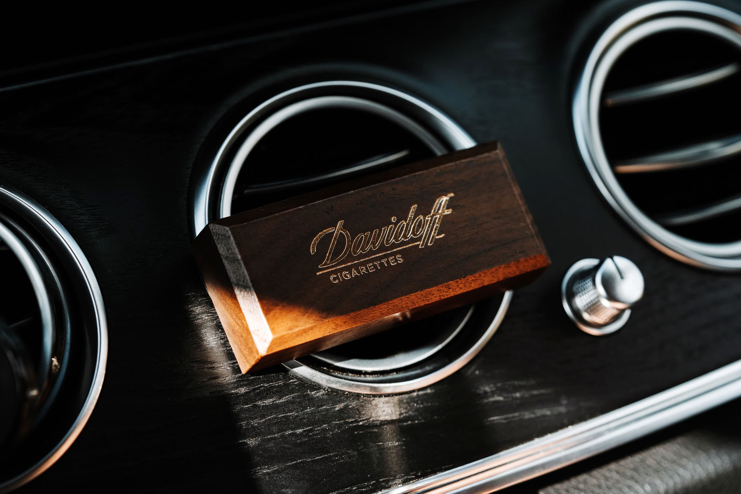 Parfum auto cu finisaj din lemn, montat pe grila de ventilație.